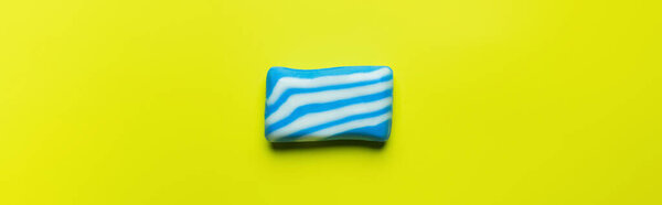 top view of bath soap with white and blue stripes on yellow background, banner