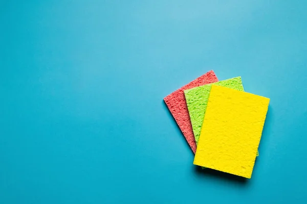 Top View Bright Yellow Green Pink Sponge Cloths Blue Background — Foto de Stock