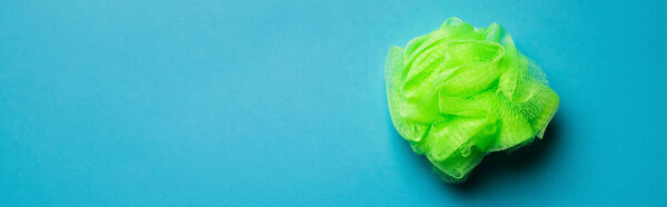 top view of bright green body washcloth on blue background with copy space, banner