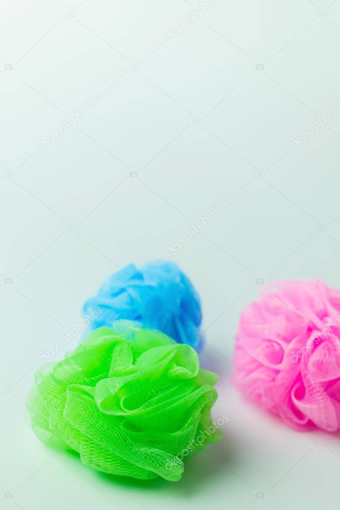 green, pink and blue mesh washcloths on grey background with copy space