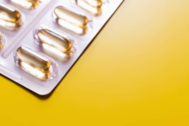 close up view of blister pack with jelly capsules isolated on yellow