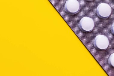 close up view of blister pack with white pills isolated on yellow with copy space