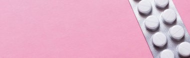 close up view of blister pack with white round shape pills isolated on pink, banner