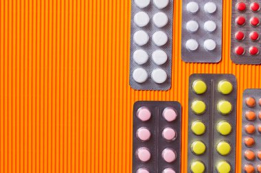 top view of blister packs with different pills on orange textured background clipart