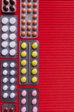 top view of blister packs with different pills on crimson textured background  clipart