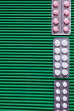 top view of blister packs with white and pink pills on green textured background clipart