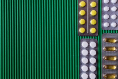 top view of blister packs with different pills and capsules on textured green background clipart