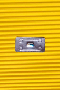 top view of blister pack with antibiotics capsule on textured yellow background