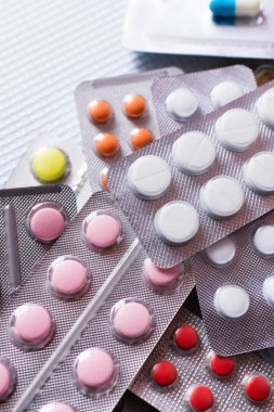 top view of blister packs with different colorful pills on white textured background 