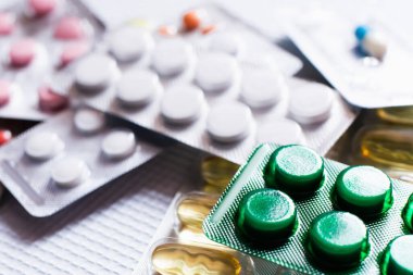 close up of blister packs with different pills and capsules on textured white background