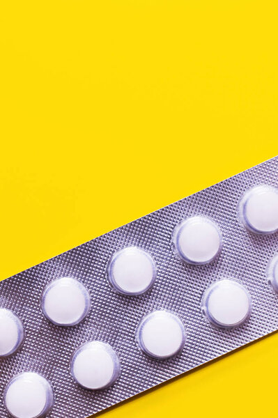 top view of blister pack with white pills isolated on yellow