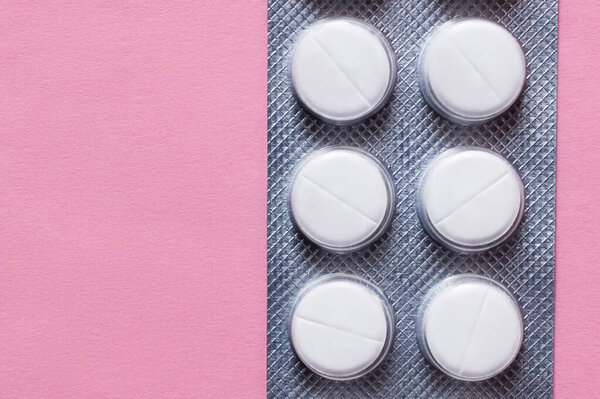 top view of blister pack with white round shape pills isolated on pink