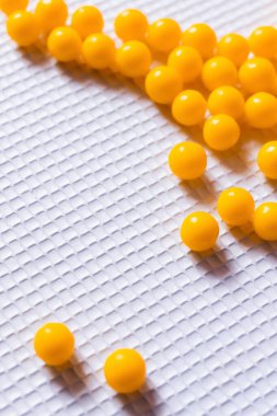 close up view of yellow round shape medication on white textured background