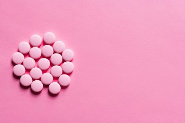 top view of pile with pills in round shape on pink background