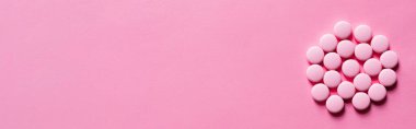 top view of pile with pills in round shape on pink background, banner