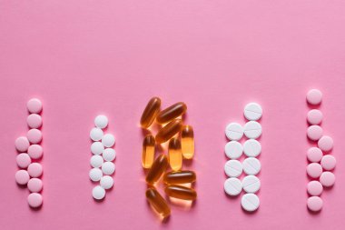 flat lay view of different round shape pills and jelly capsules on pink background clipart