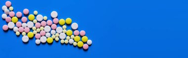 flat lay view of different round shape pills on blue background, banner