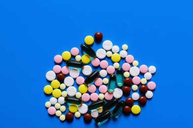 top view of different colorful pills and capsules on bright blue background clipart