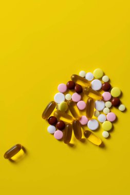 top view of colorful pills and jelly capsules on yellow background clipart