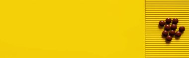 top view of pile with brown round shape pills on yellow textured background, banner