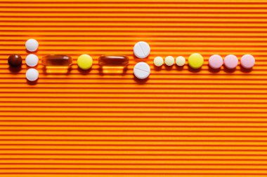 flat lay of different pills on orange textured background clipart