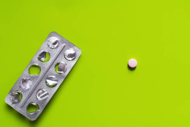 top view of used blister pack near round shape pill on green background 