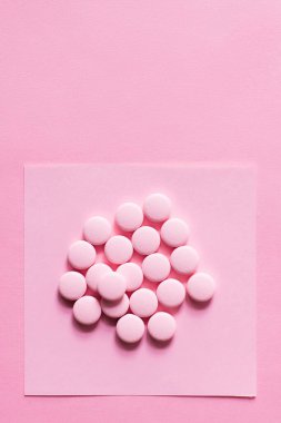 Pembe üzerine izole edilmiş kağıt üzerinde yuvarlak şekilli hapların üst görünümü