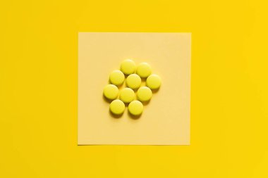 top view of round shape pills on paper note on yellow