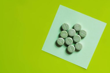 top view of round shape pills on paper note on green
