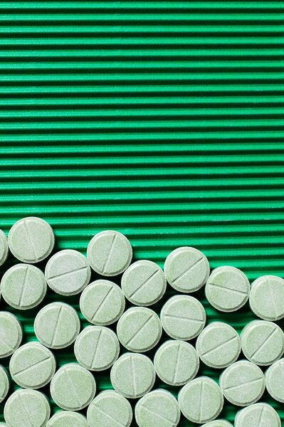 top view of round shape medication on textured green background