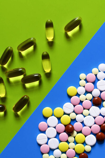 top view of different colorful pills and jelly capsules on bright blue and green background