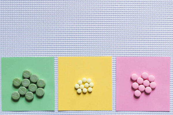 top view of colorful round shape pills on paper notes on textured white background