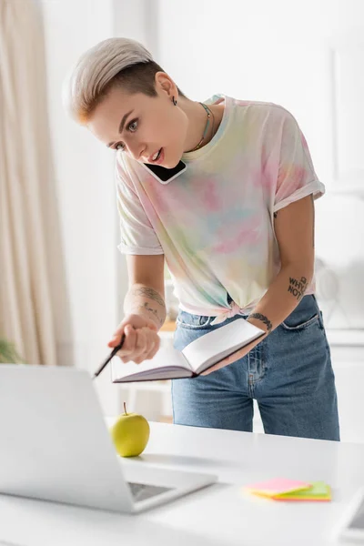 Young Woman Notebook Pen Talking Mobile Phone Blurred Laptop — Stockfoto