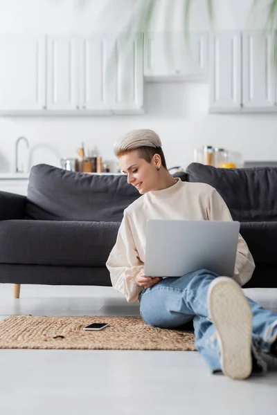 Mujer Sonriente Sentada Suelo Con Portátil Mirando Teléfono Inteligente Con — Foto de Stock