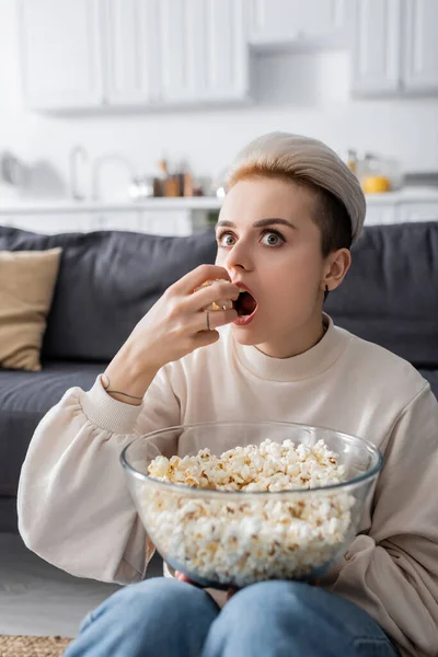 驚くべき女性がテレビを見て家でポップコーンを食べて — ストック写真