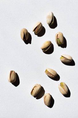 top view of cracked green and salty pistachios on white background 