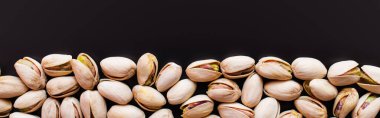 top view of fresh and salty pistachios isolated on black, banner