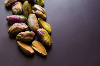 close up view of green and salty pistachios without shell on black 