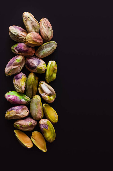 top view of green and salty pistachios without shell isolated on black 