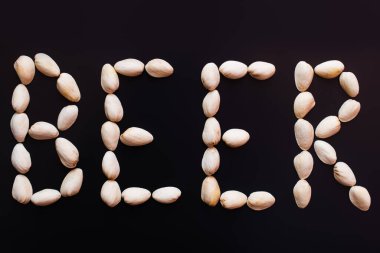 top view of beer word made of pistachio nutshells isolated on black 