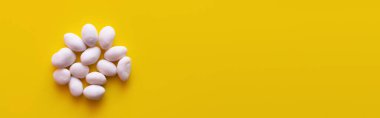 top view of peeled pine nuts on yellow background, banner