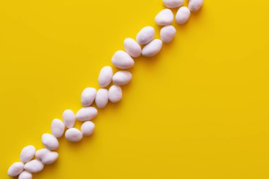 top view of row with peeled pine nuts on yellow background