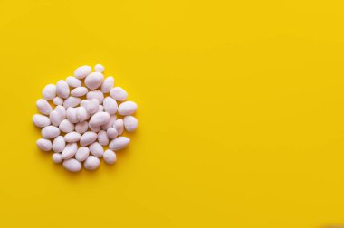 top view of pile with peeled pine nuts on yellow background