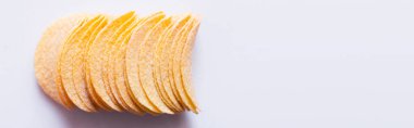 top view of salty and crunchy potato chips on white, banner
