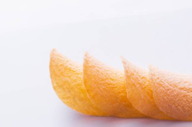 close up of stacked and fried potato chips on white background 