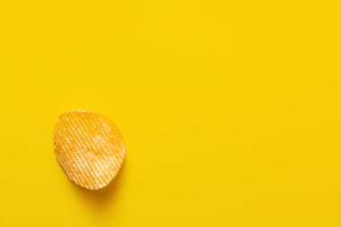 top view of single wavy and salty potato chip on yellow clipart