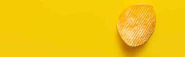 top view of single wavy and salty potato chip on yellow, banner clipart