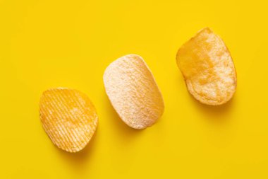 top view of different salty potato chips on yellow clipart