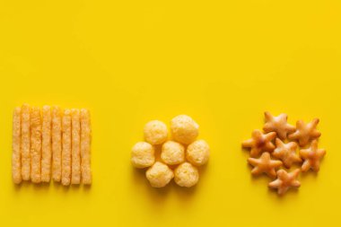 top view of tasty french fries, cheese pops and bakes star shape cookies on yellow clipart