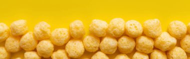 top view of puffed and tasty cheese pops on yellow, banner clipart